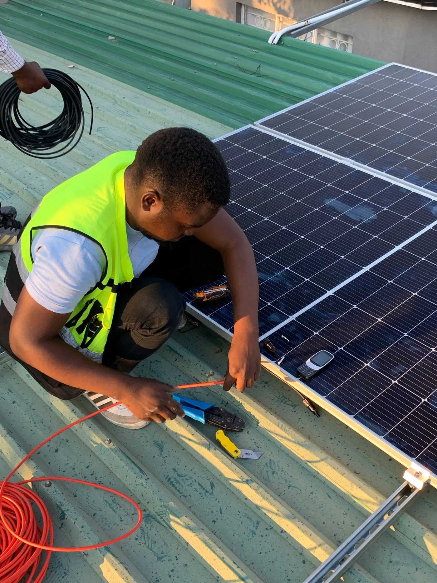 Technician in high-visibility gear installing a solar panel on a roof